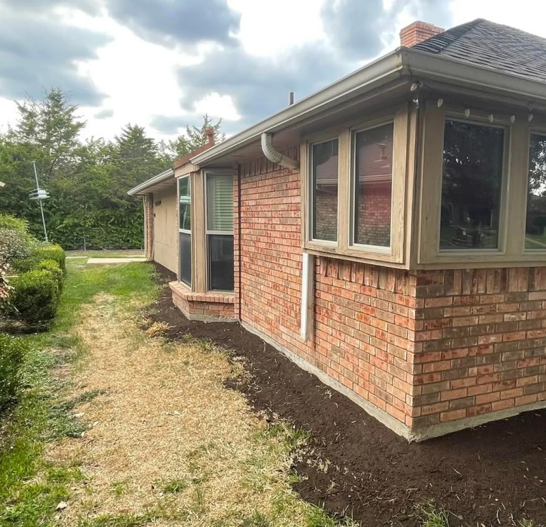 A brick house with a newly mulched garden bed